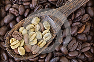 Dried raw unroasted green coffee berry seeds on top of roasted c