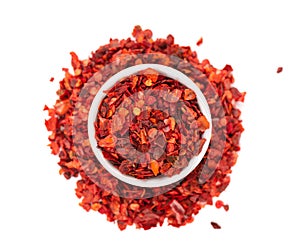 Dried red chili flakes in bowl, isolated on white background. Chopped chilli cayenne pepper. Spices and herbs. Top view.