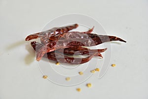 Dried red chilli seeds are an ingredient in cooking, placed on a white background.