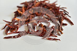 Dried red chilli seeds are an ingredient in cooking, placed on a white background.