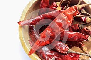 Dried red hot chili pepper in the wooden bowl isolated on white background.