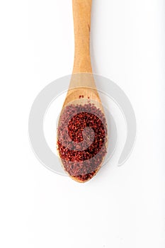 Dried red pepper flakes in the wooden spoon on white background.