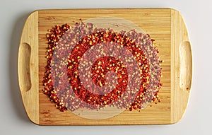 Dried red pepper powder. Background of crushed dry chili peppers on a wooden board