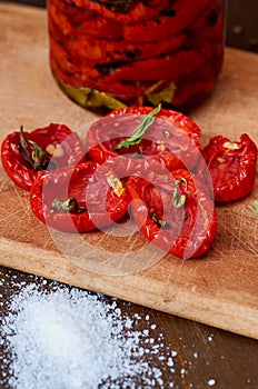 Dried red tomatoes with salt, spices and herbs on wooden board close up