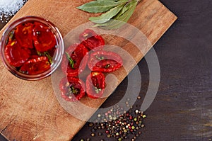 Dried red tomatoes with salt, spices and herbs on wooden board. Top view with copy space