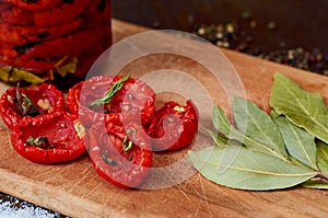 Dried red tomatoes with spices and herbs on wooden board