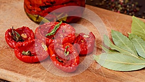 Dried red tomatoes with spices and herbs on wooden board close up