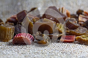 Dried rhubarb candied fruits. Candied rhubarb on a canvas fabric background. Dry rhubarb close - up macro photography. Rheum