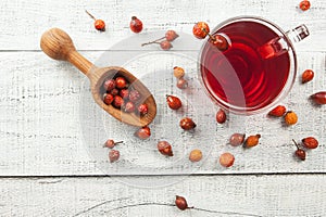 Dried rose hip cup of herbal tea medicinal plants with wooden shovel on white black wooden vintage table , rosehips. Dogrose backg