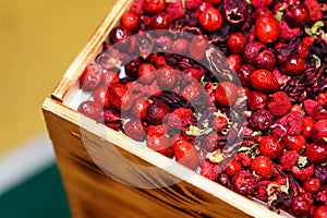 Dried rose hips and flower petals in a wooden box. Healthy products for making hot drinks. Wholesale and retail trade in berries.