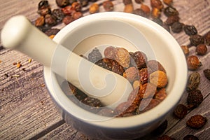 Dried rosehip fruit in a ceramic mortar and dried rosehip fruit in bulk on a wooden background. Close up