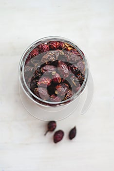 Dried rosehips in a jar on a light background, close-up