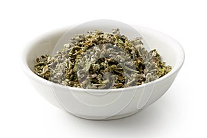 Dried rubbed sage in a white ceramic bowl isolated on white