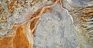 Dried rusty river bed over wasteland grey background, contamination texture, view directly above