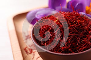Dried saffron and crocus flowers on wooden tray, closeup. Space for text