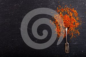 Dried saffron spice in a spoon on dark background