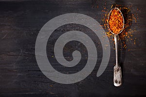 Dried saffron spice in a spoon on wooden table