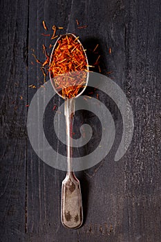 Dried saffron spice in a spoon on wooden table