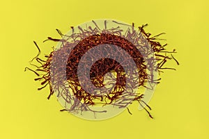 Dried Saffron threads on yellow background.