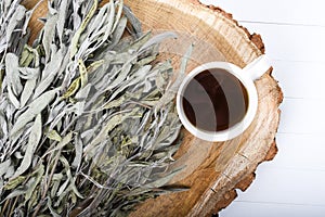 Dried sage branches, sage hot tea, on a piece of natural wood, natural remedies, natural medicine