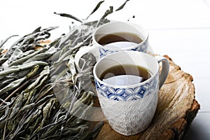 Dried sage branches, sage hot tea, on a piece of natural wood, natural remedies, natural medicine