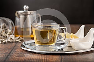 Dried sage tea in glass cup on wooden table