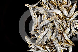 Dried salted small fish on black background