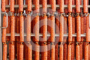 Dried sausage hanging on a rope on a metal frame in the smoke house.