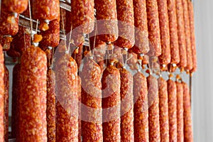 Dried sausage hanging on a rope on a metal frame in the smoke house.