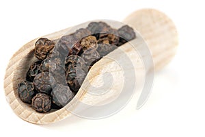 Dried seeds of black pepper on a wooden spatula.