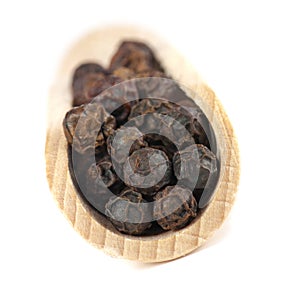 Dried seeds of black pepper on a wooden spatula.