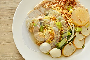 Dried spicy Chinese egg noodles topping fish and shrimp ball with slice boiled pork on plate