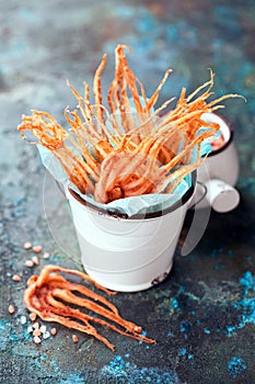 Dried squid tentacles snack with hot spices in a ceramic bucket
