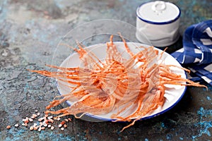 Dried squid tentacles snack with hot spices on a plate