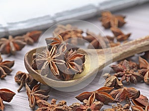 Dried star anise in a spoon and on a table