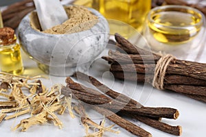 Dried sticks of licorice roots, shavings and powder on white table, closeup