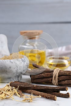 Dried sticks of licorice roots and shavings on white table, closeup. Space for text