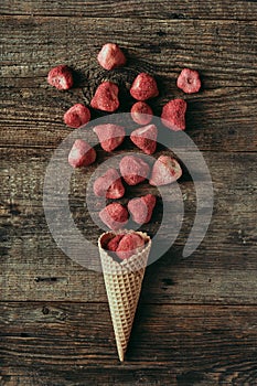 Dried strawberries in waffle cone on wooden table, healthy snack, concept flat lay photography and content for food blog