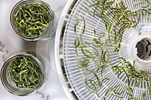 Dried string beans on a dehydrating tray and in jars for food preservation