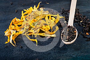 Dried sunflower petals on dark background and tea leaves