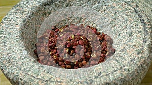 Dried szechuan or sichuan pepper in a stone mortar close up