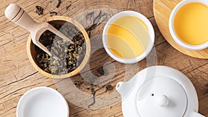 Dried tea leaves with teapot and tea cup on wood table