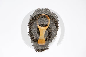 Dried tea leaves writing tea word with wooden spoon isolated over a wite background.