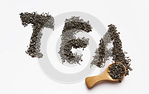Dried tea leaves writing tea word with wooden spoon isolated over a wite background.