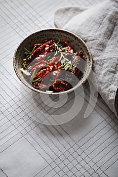 Dried tomatoes in a bowl with fresh spices and olive oil
