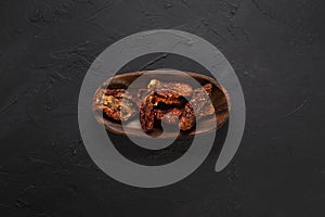 Dried tomatoes concept with wooden presentation board on black stone floor ( with copy space