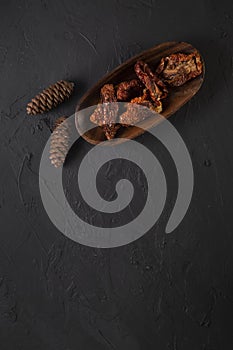 Dried tomatoes concept with wooden presentation board on black stone floor ( with copy space