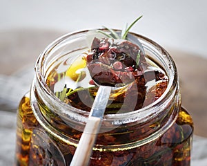 Dried tomatoes in a jar with fresh spices and olive oil