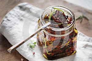 Dried tomatoes in a jar with fresh spices and olive oil