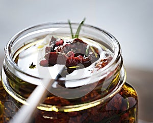 Dried tomatoes in a jar with fresh spices and olive oil